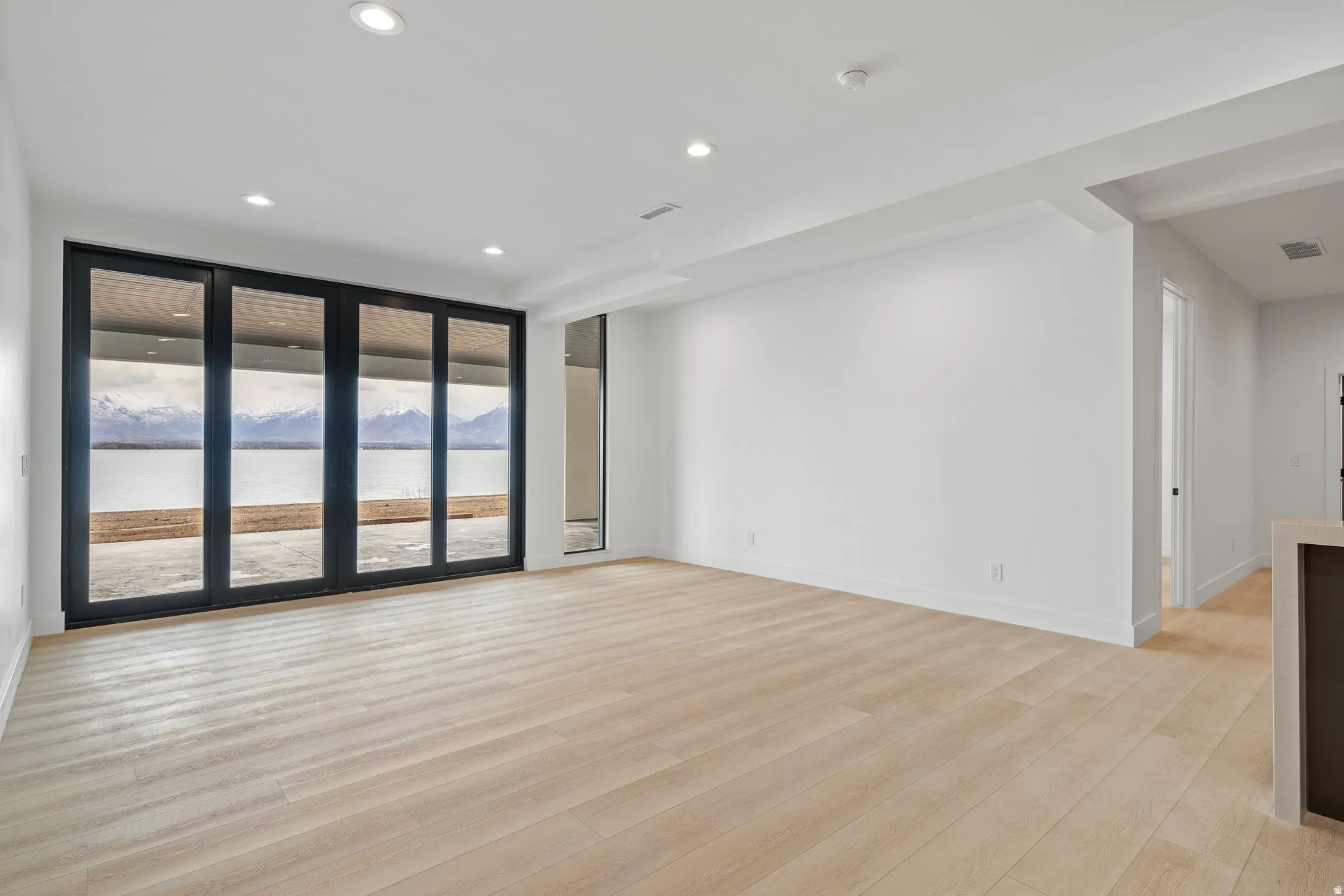 Expansive space featuring light wood-finish flooring, recessed lighting, and a wall of multi-panel sliding glass doors