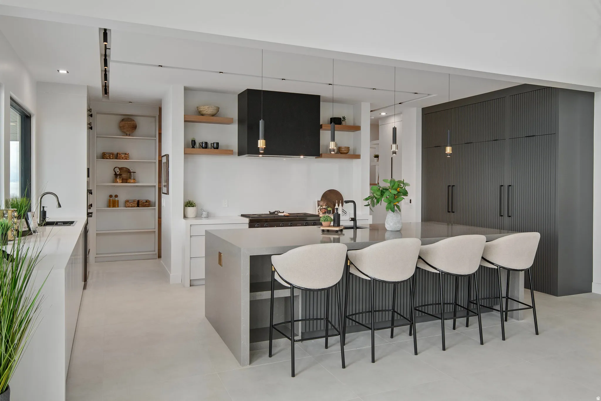 Expansive kitchen featuring a large central island, integrated appliances, built-in shelving, and contemporary pendant lighting