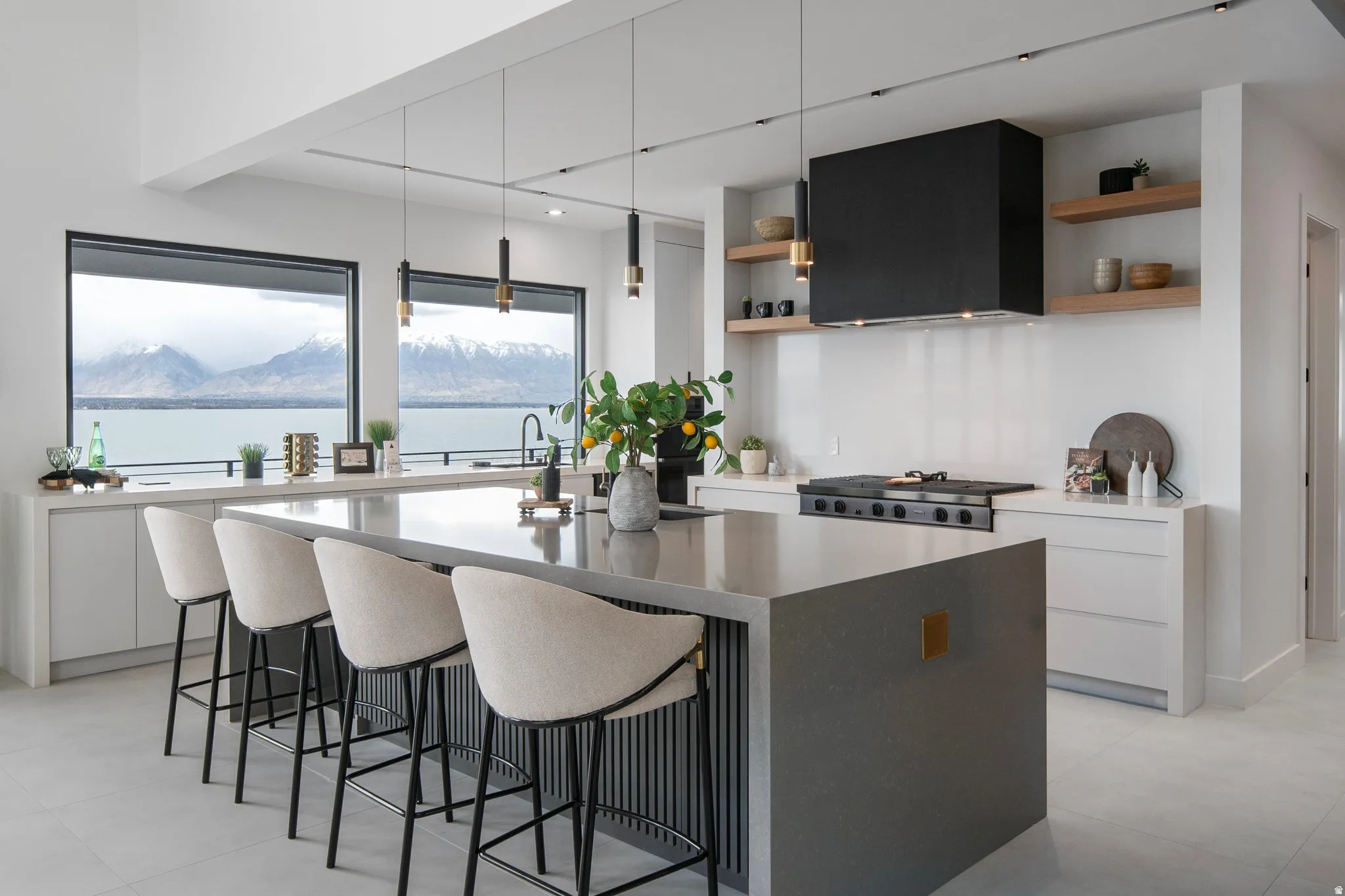 Spacious kitchen featuring an expansive island, integrated cooktop, custom range hood, and open shelving