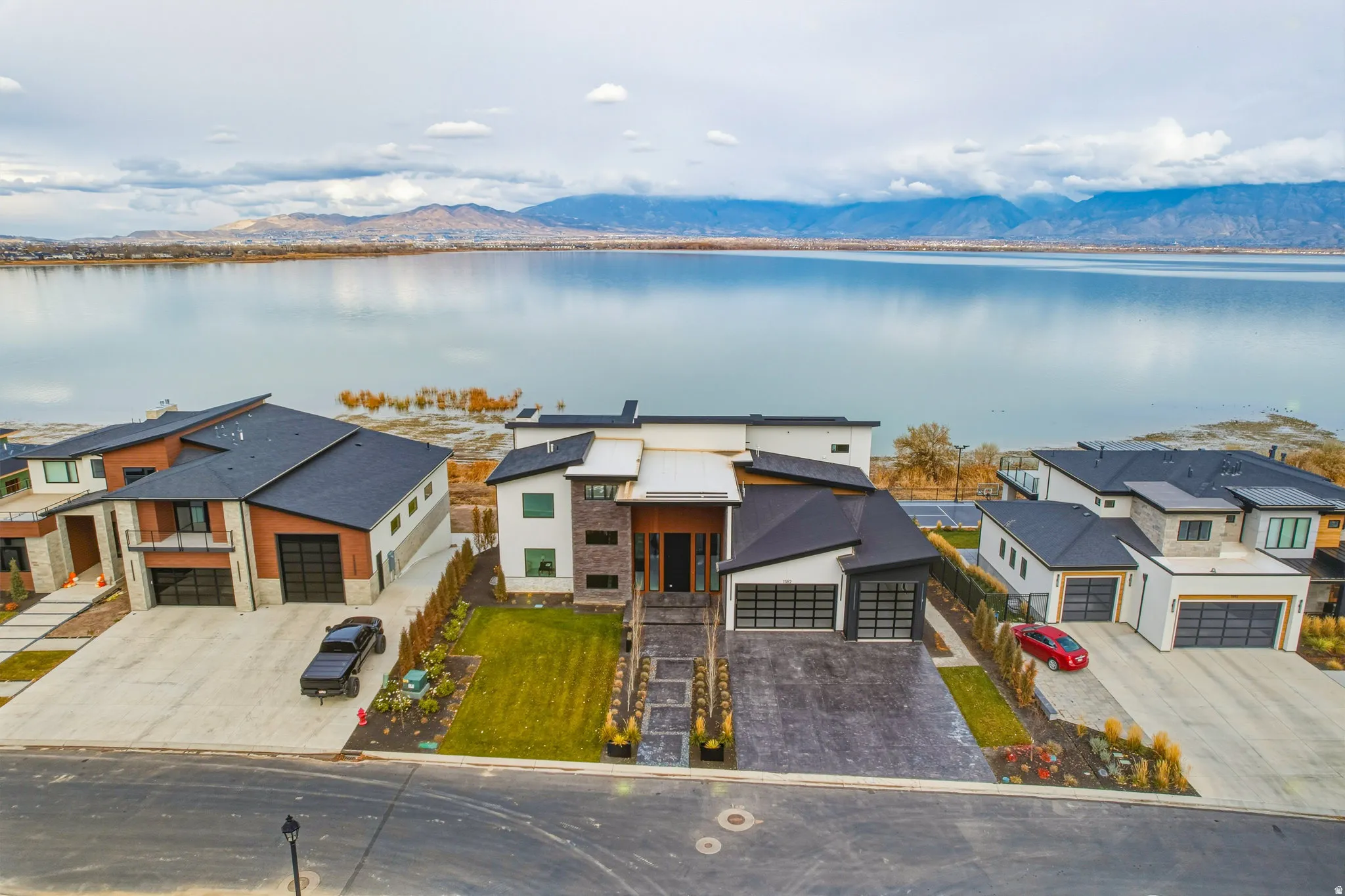 Contemporary architectural design with a dark roof and light-colored siding, a multi-car garage, and a concrete driveway