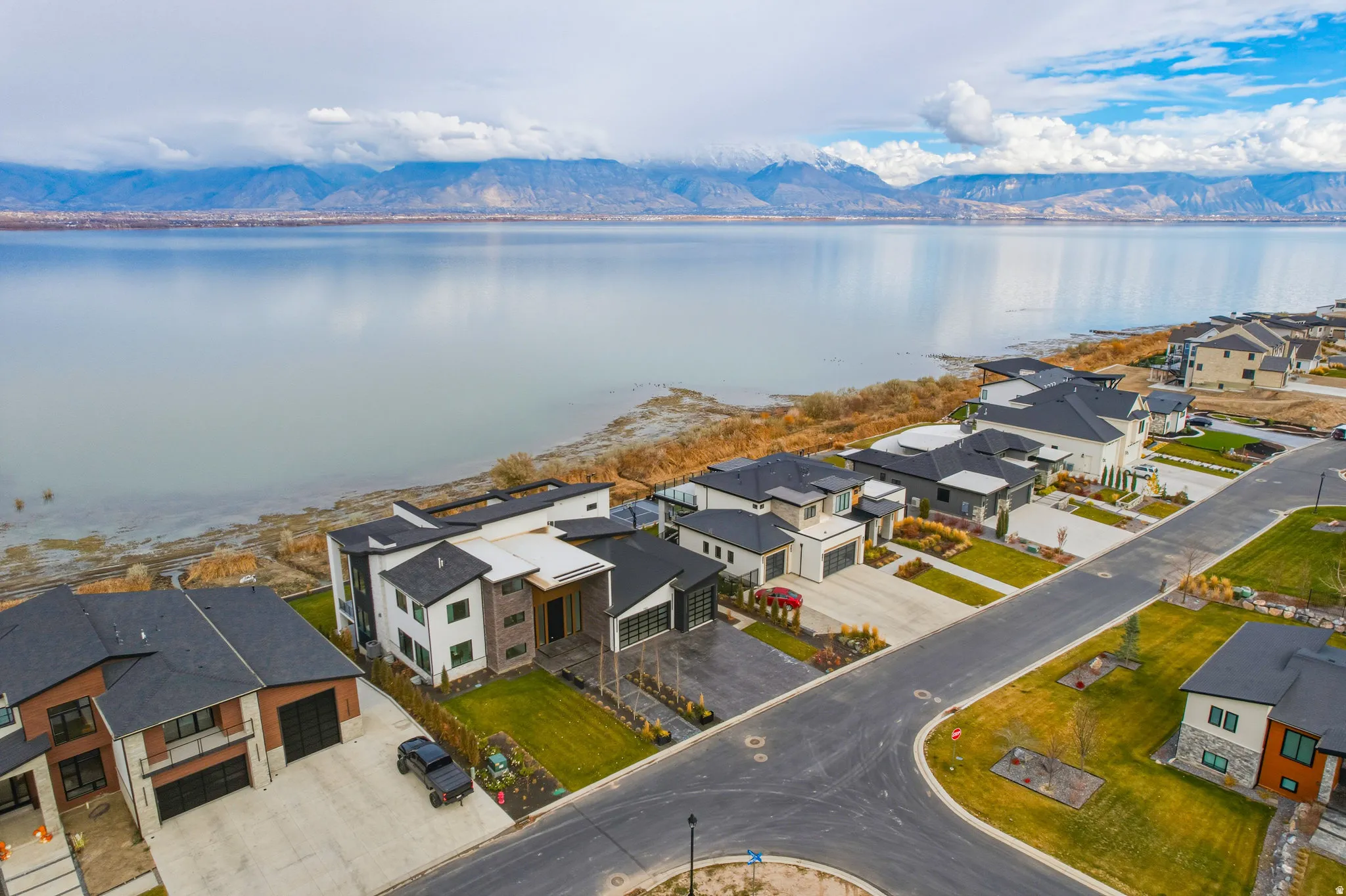 Lakeside community with modern architectural styles, paved roadways, and landscaped lots