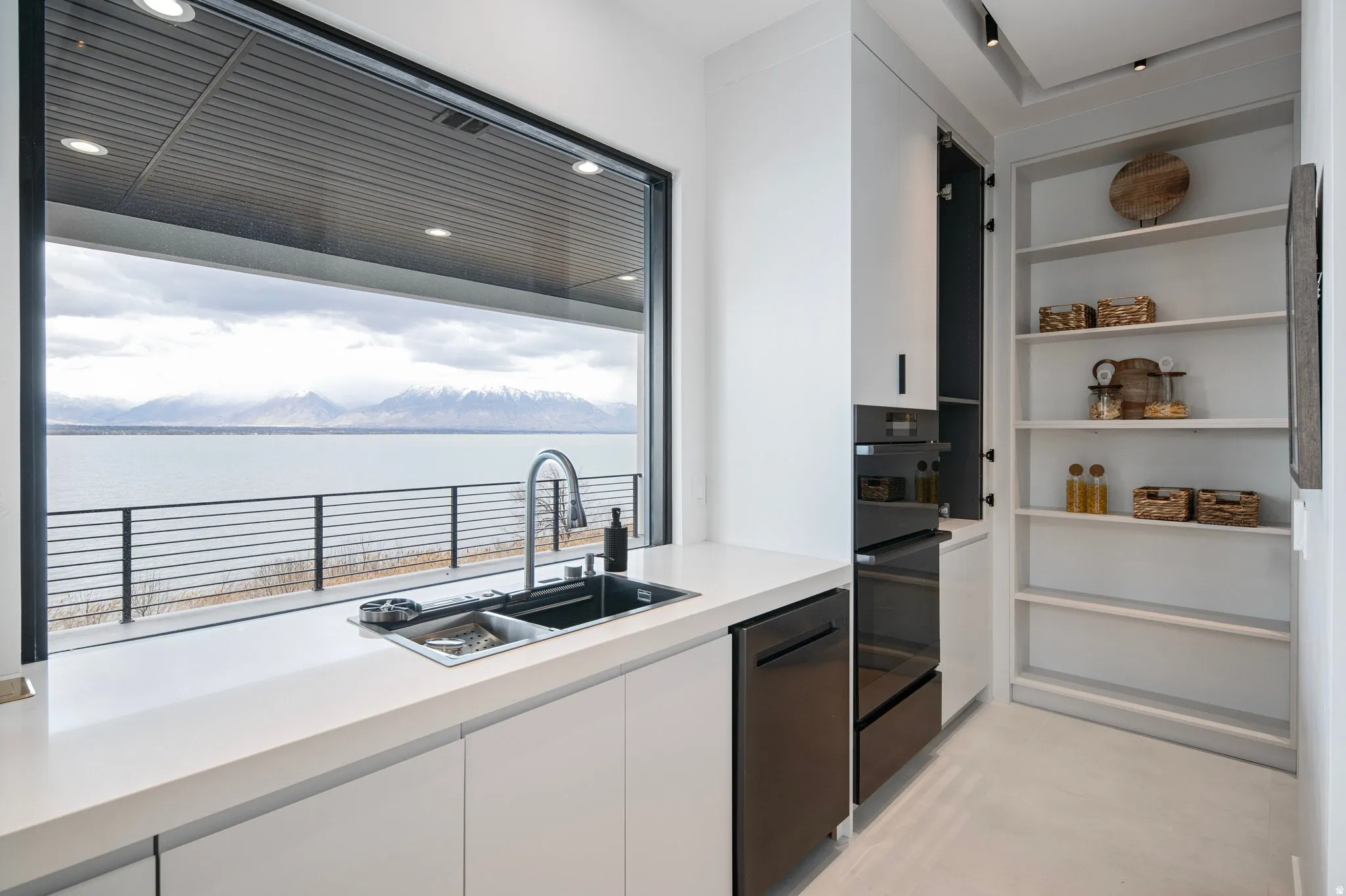 Expansive kitchen featuring a large window, integrated sink, built-in oven, integrated dishwasher, and open shelving