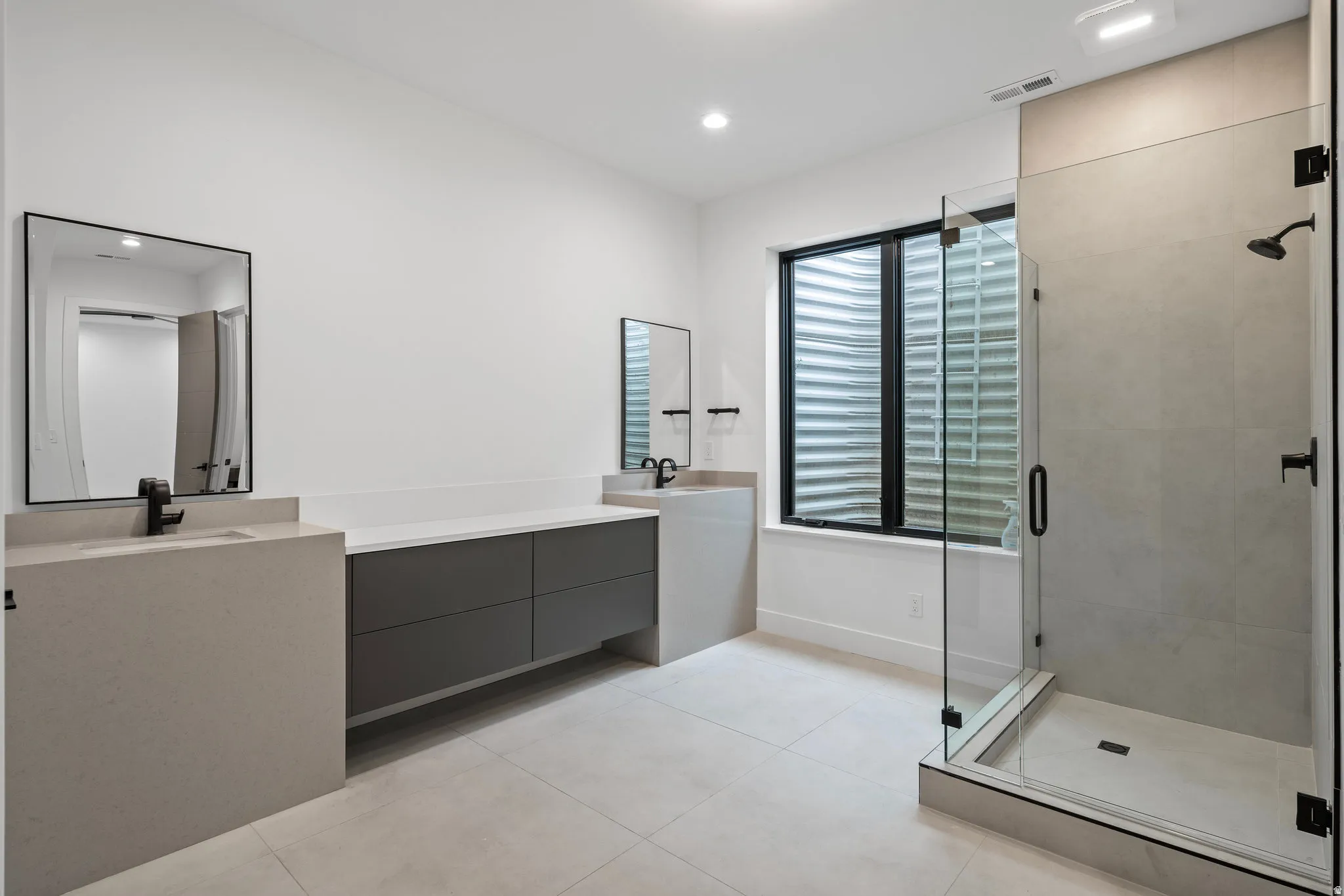 Dual vanity with light-toned countertops, dark gray cabinetry, and matte black fixtures