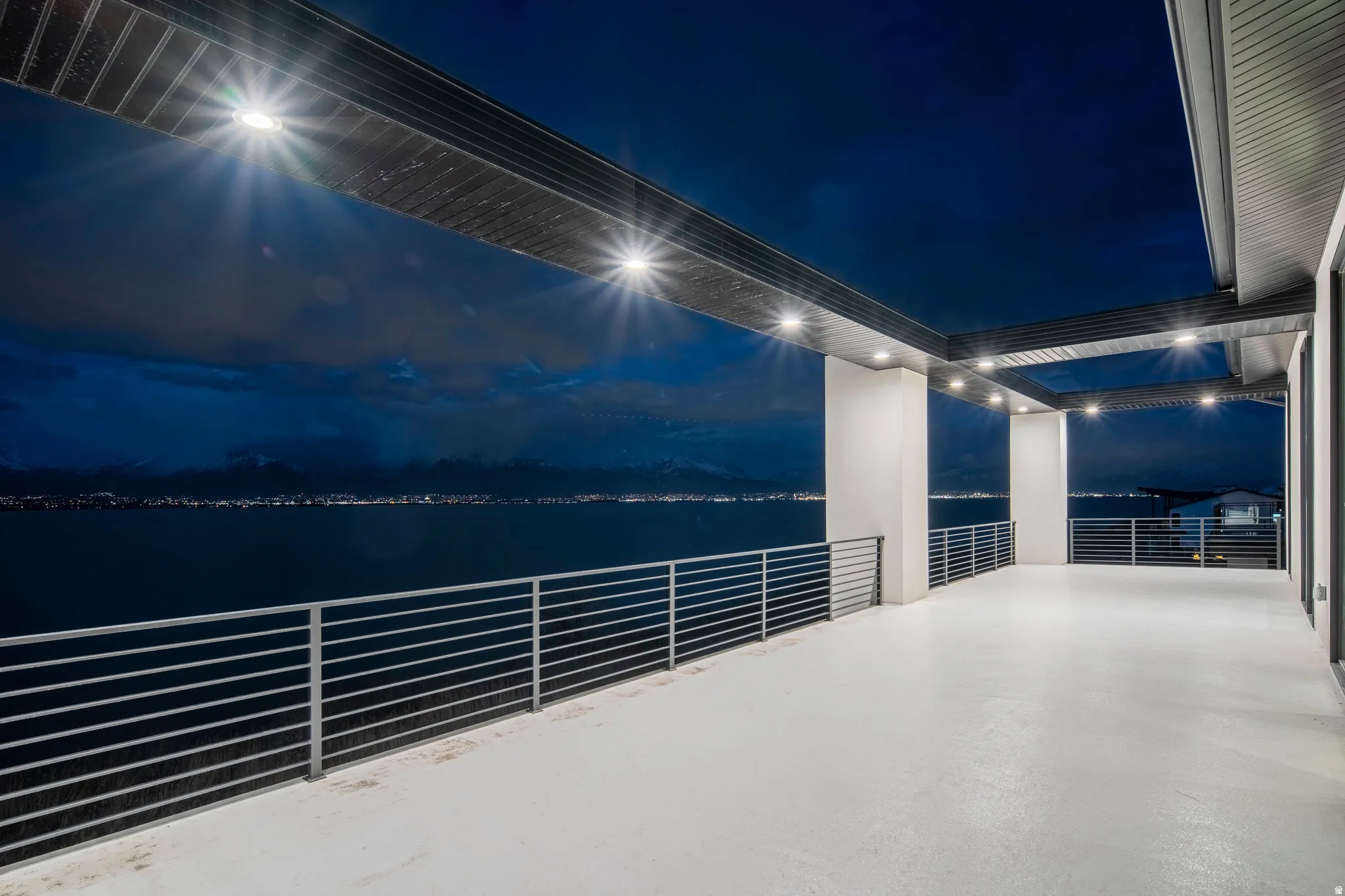 Expansive waterfront balcony with a protective overhang and recessed lighting