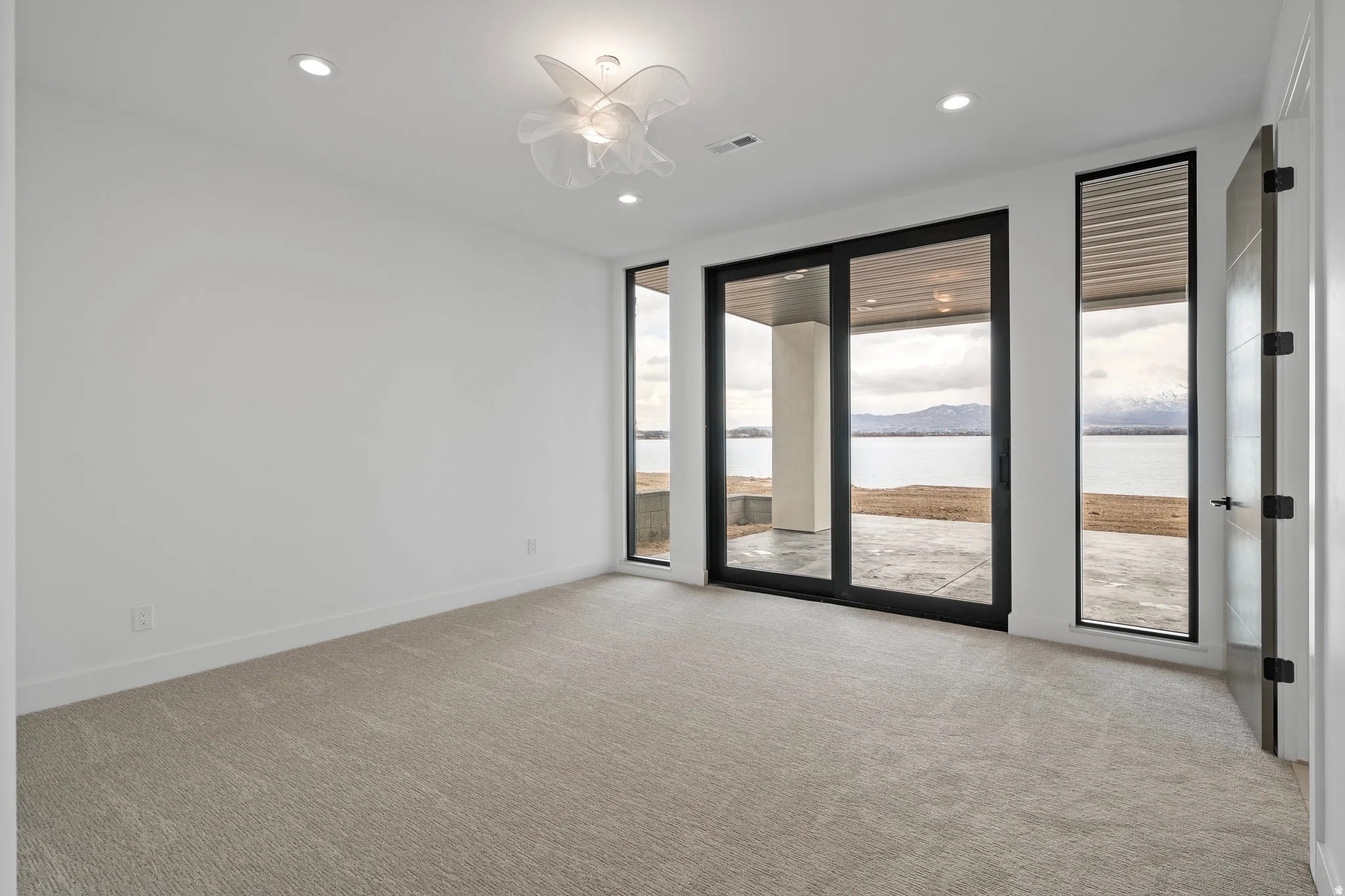 Recessed lighting, contemporary ceiling fixture, carpet flooring, sliding glass doors, and a vertical window