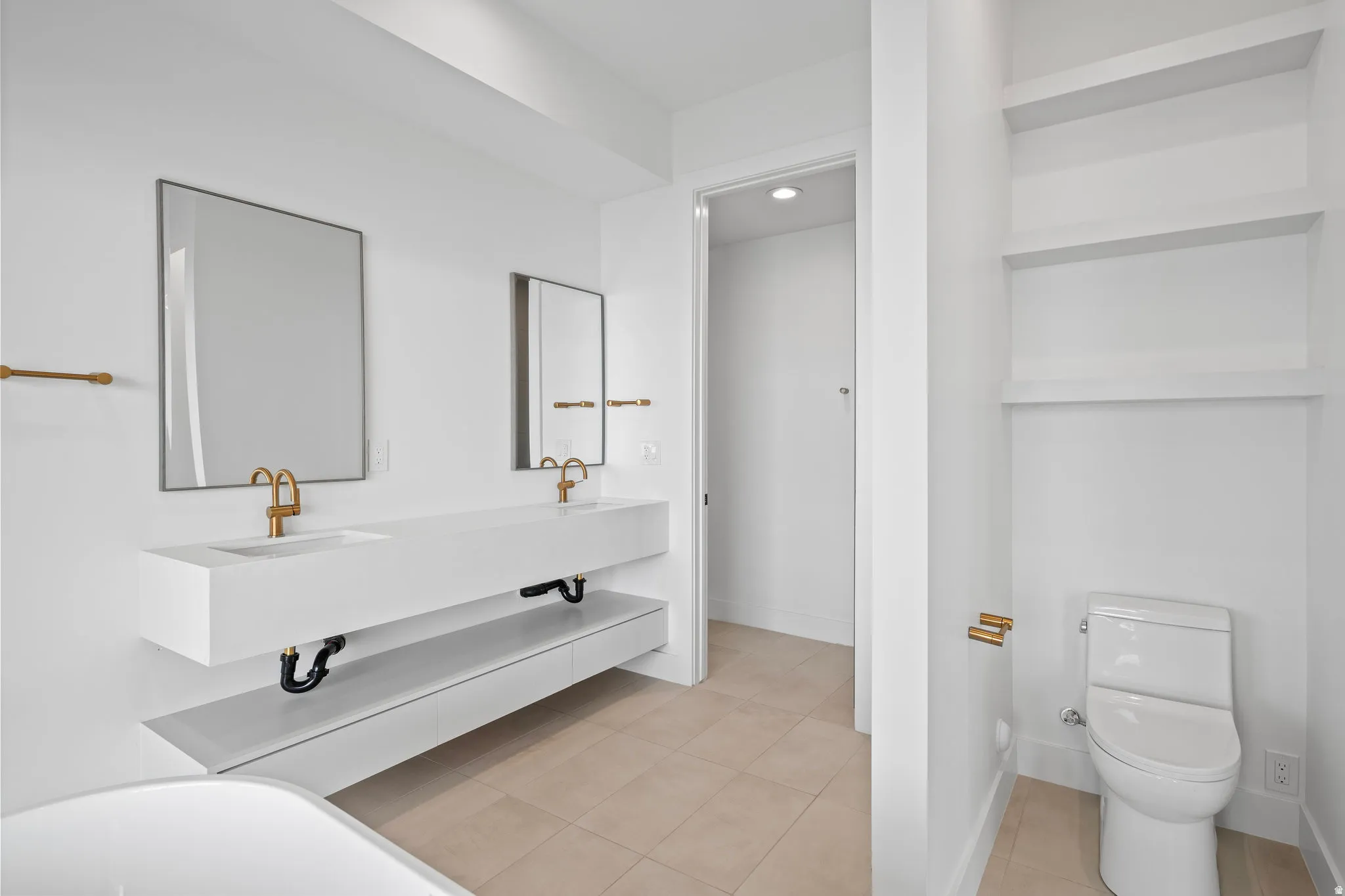Dual floating vanities with integrated rectangular sinks, gold-finish fixtures, and individual framed mirrors