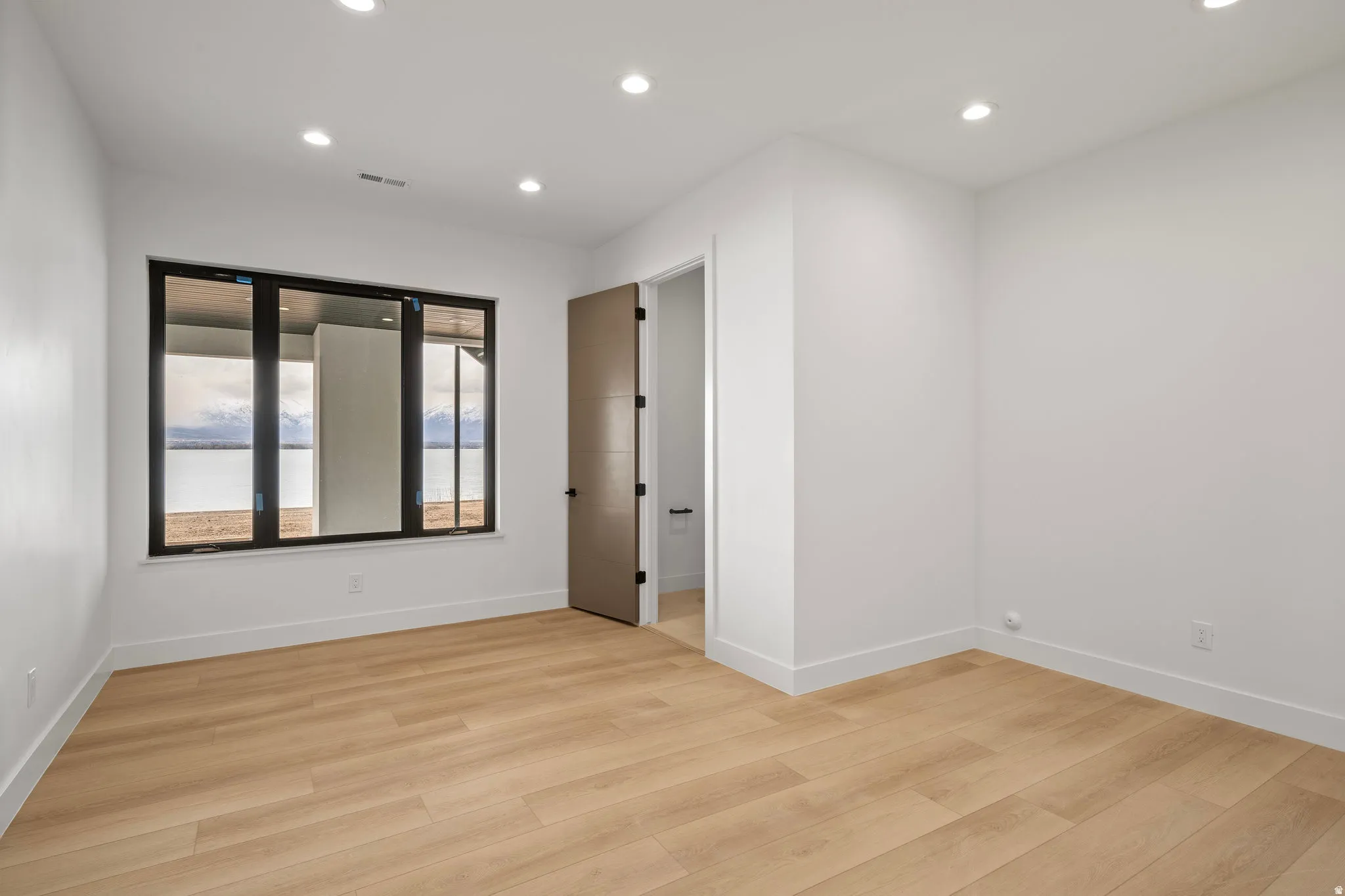 Recessed lighting, wood-finish flooring, and a large window with black framing