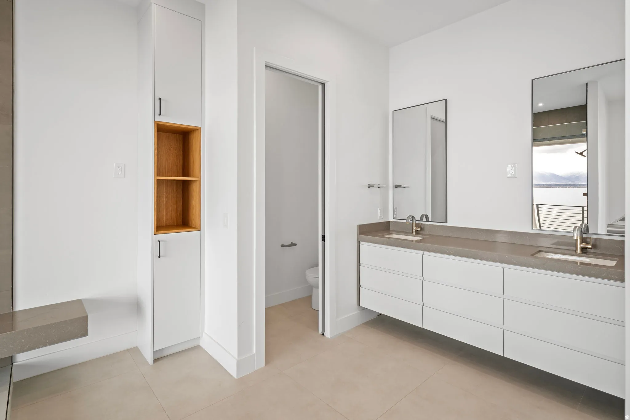 Dual vanities with integrated sinks, stone countertops, and wall-mounted mirrors