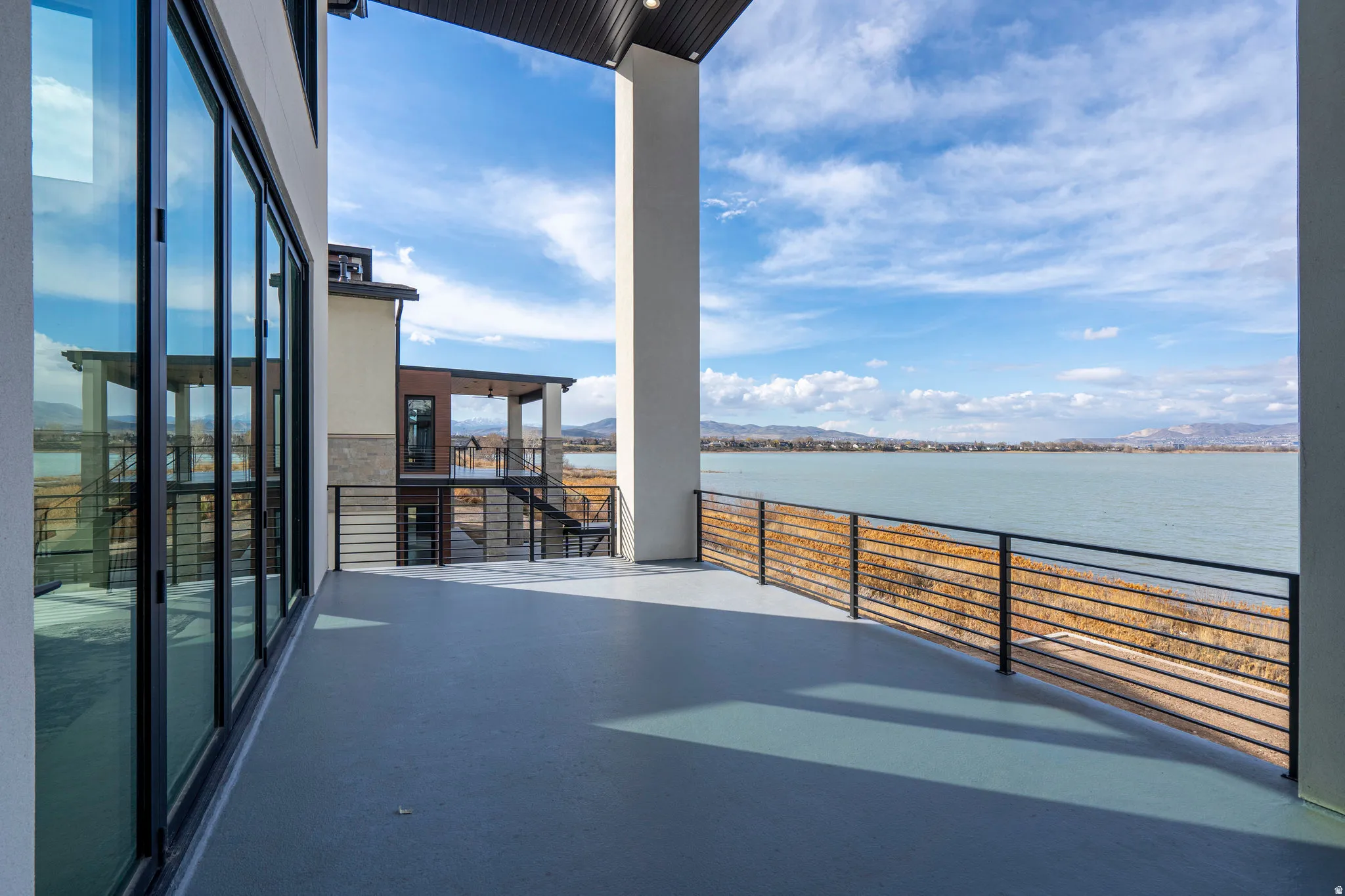 Expansive outdoor deck with a durable surface, full-height glass doors, and a horizontal bar railing
