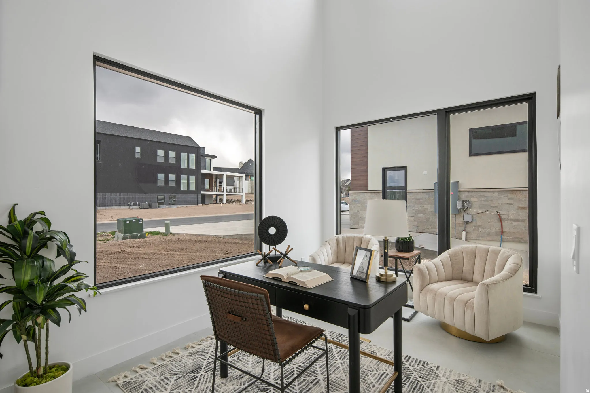 Vaulted ceiling, expansive windows with black frames, white walls, and light-toned flooring