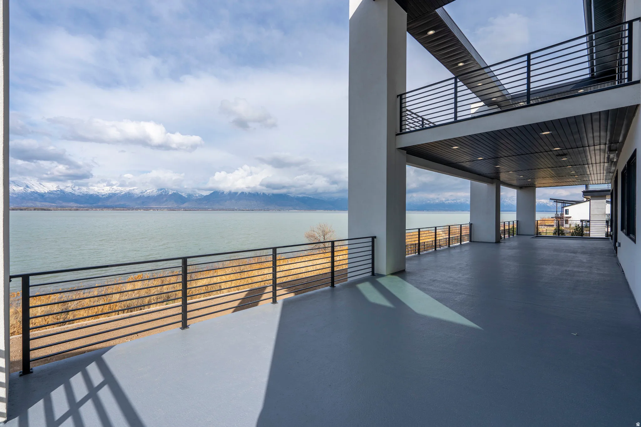 Spacious outdoor deck with modern horizontal railings, overlooking a large body of water