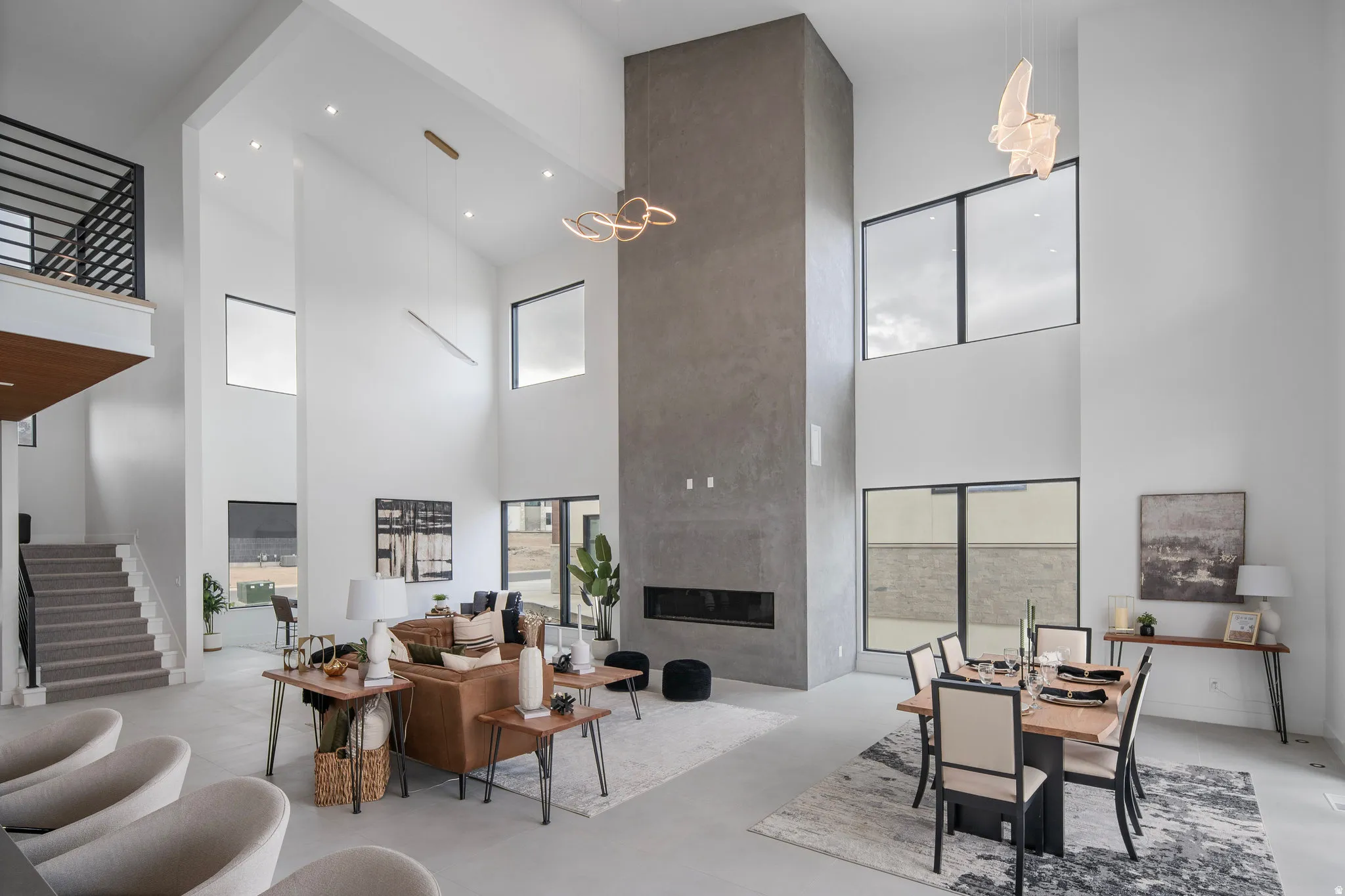Open-concept living space featuring a two-story ceiling, a floor-to-ceiling fireplace with a linear insert, and large windows