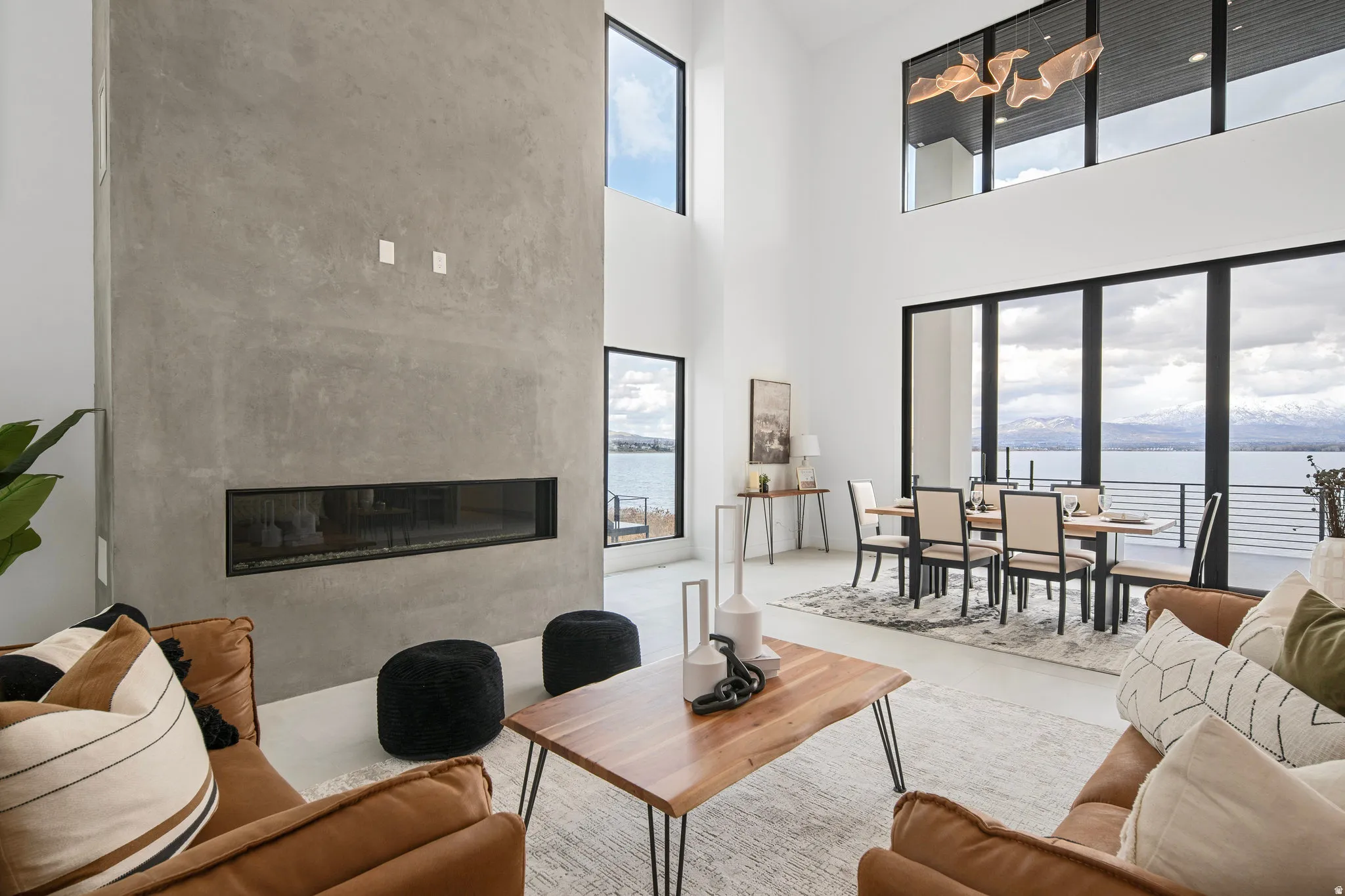 Two-story living area with a floor-to-ceiling fireplace, expansive windows, a dining area, and a white ceiling