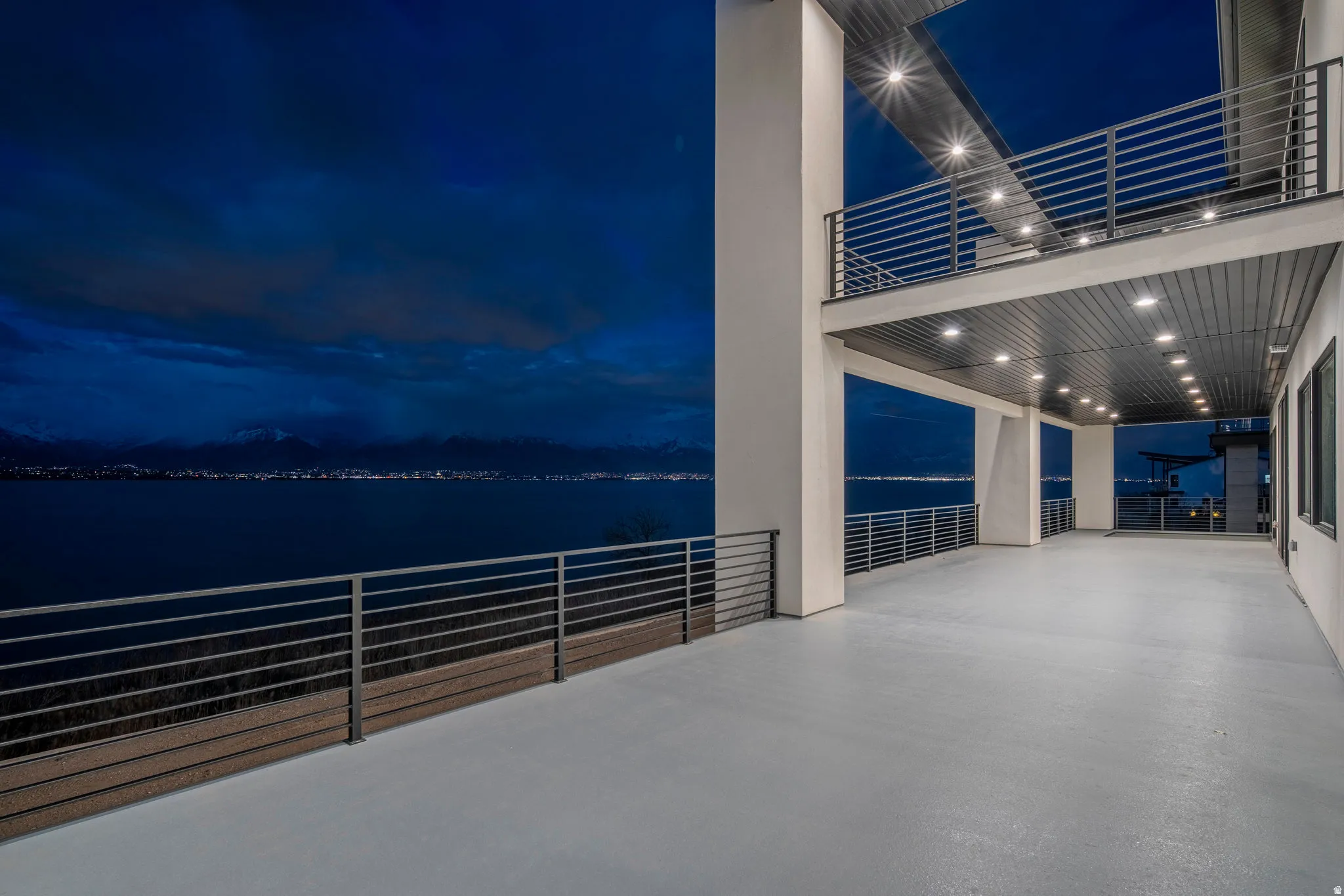 Expansive outdoor deck with a painted surface, metal railings, and integrated overhead lighting