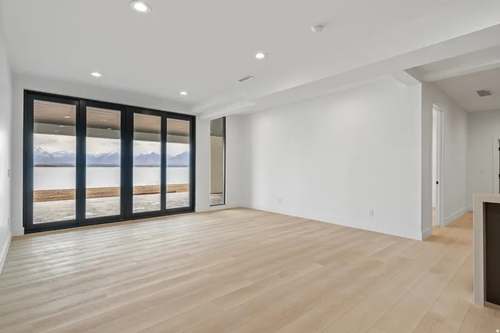 Expansive space featuring light wood-finish flooring, recessed lighting, and a wall of multi-panel sliding glass doors