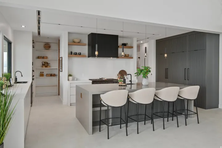 Expansive kitchen featuring a large central island, integrated appliances, built-in shelving, and contemporary pendant lighting