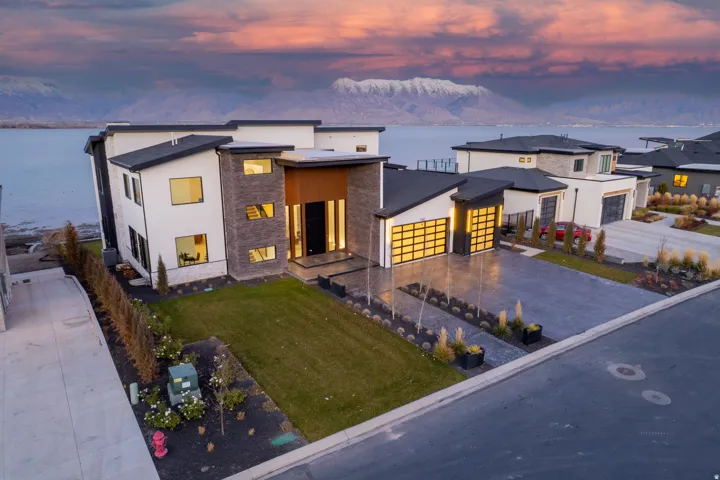 Modern architecture featuring a multi-tone facade, expansive windows, a two-car garage with translucent doors, and a paved driveway