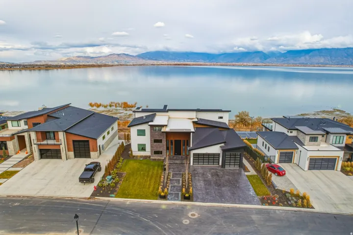 Contemporary architectural design with a dark roof and light-colored siding, a multi-car garage, and a concrete driveway