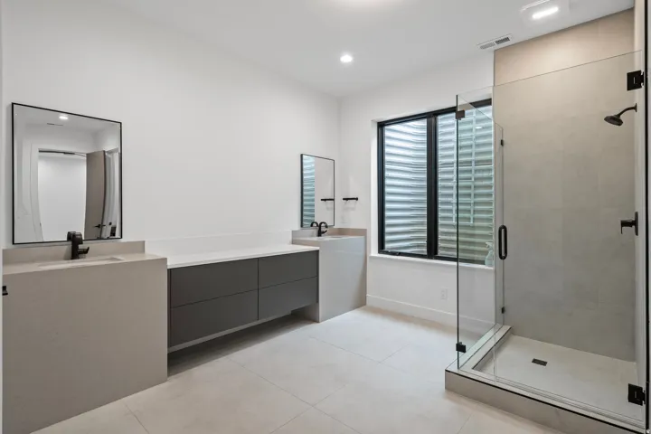 Dual vanity with light-toned countertops, dark gray cabinetry, and matte black fixtures