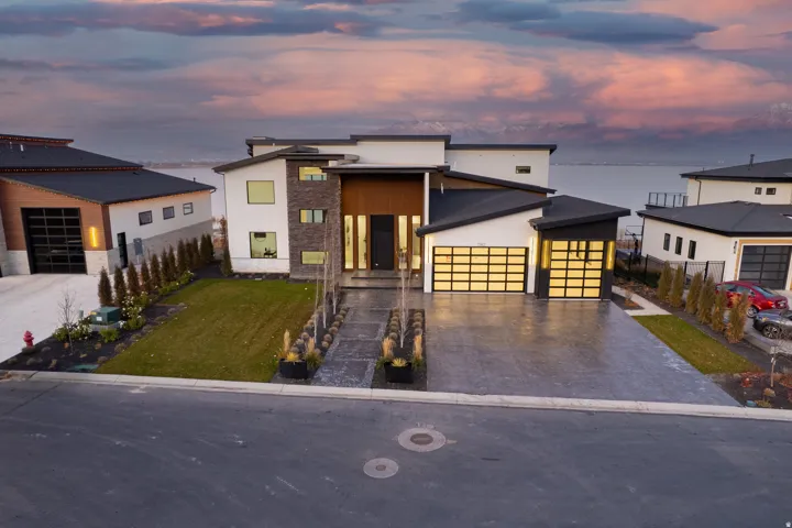 Modern architectural design featuring varied exterior finishes, an integrated two-car garage with glass-paneled doors, and a concrete driveway