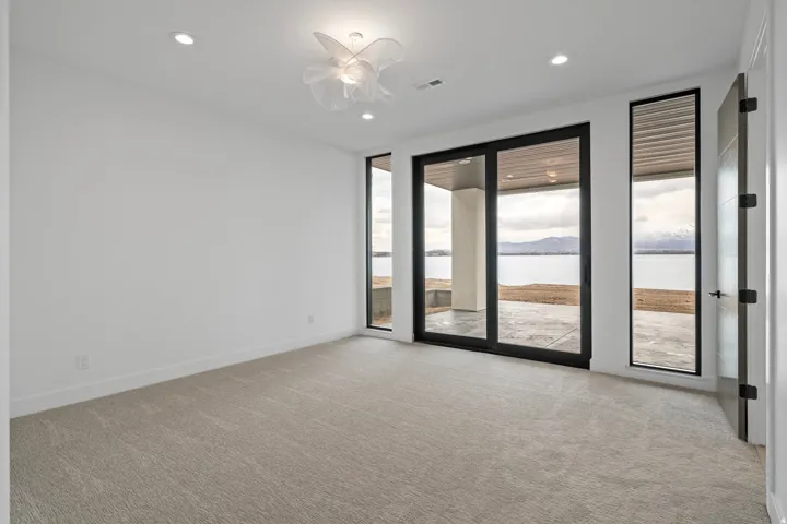 Recessed lighting, contemporary ceiling fixture, carpet flooring, sliding glass doors, and a vertical window