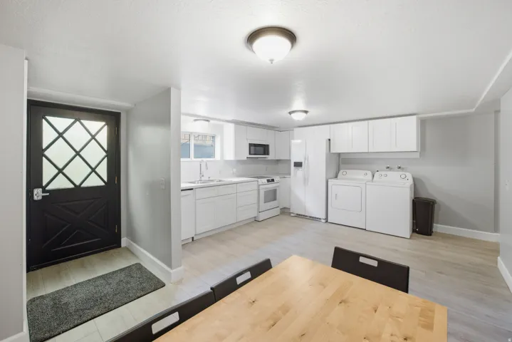 Modern kitchen with white cabinetry, light wood-finish flooring, and white appliances