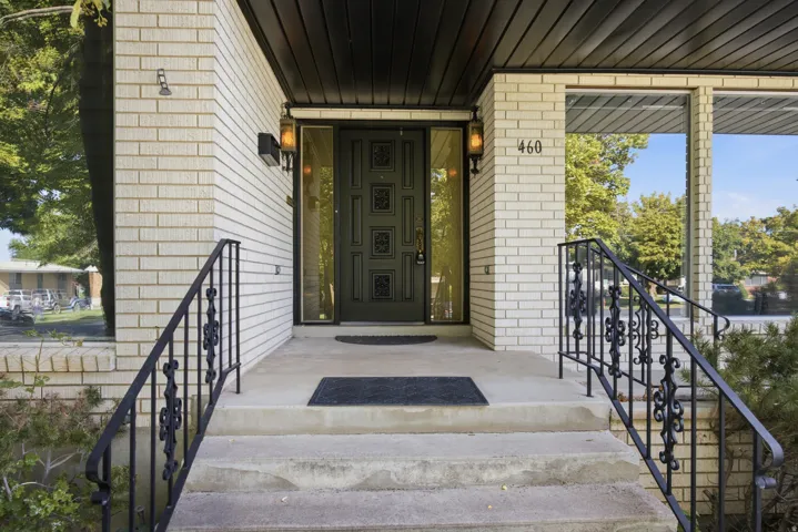 White brick exterior with a black paneled ceiling, concrete porch, and wrought iron railings