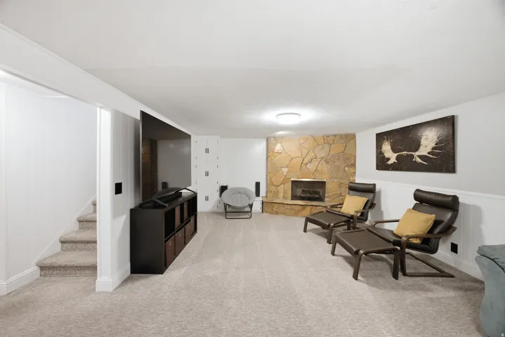 Stone-faced fireplace, recessed lighting, carpeted flooring, and built-in white cabinetry