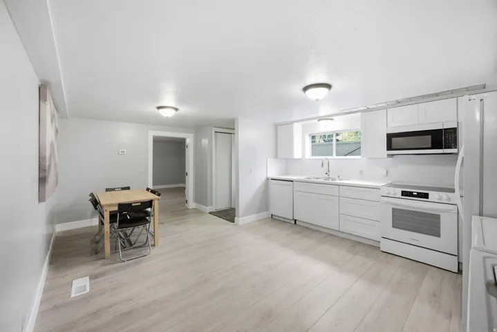 Open-concept kitchen with white cabinetry and appliances, light-toned wood-finish flooring, and recessed overhead lighting