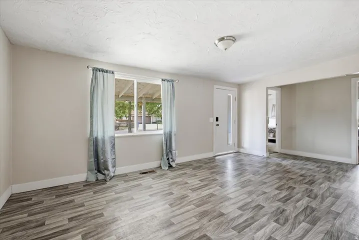 Wood-finish flooring, white walls, and a window with white trim