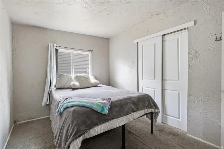Wall-to-wall carpeting, window with horizontal blinds, and a sliding two-panel closet door