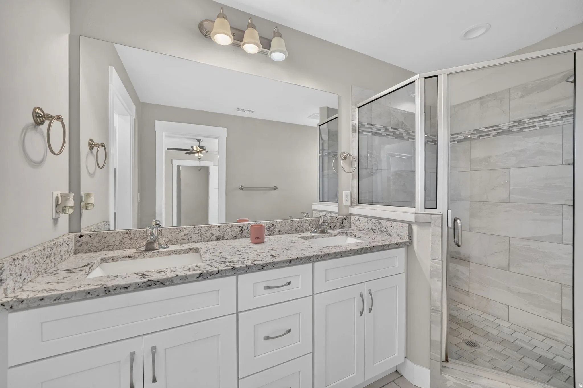 Dual vanity with stone-finish countertop, white cabinetry, and undermount sinks