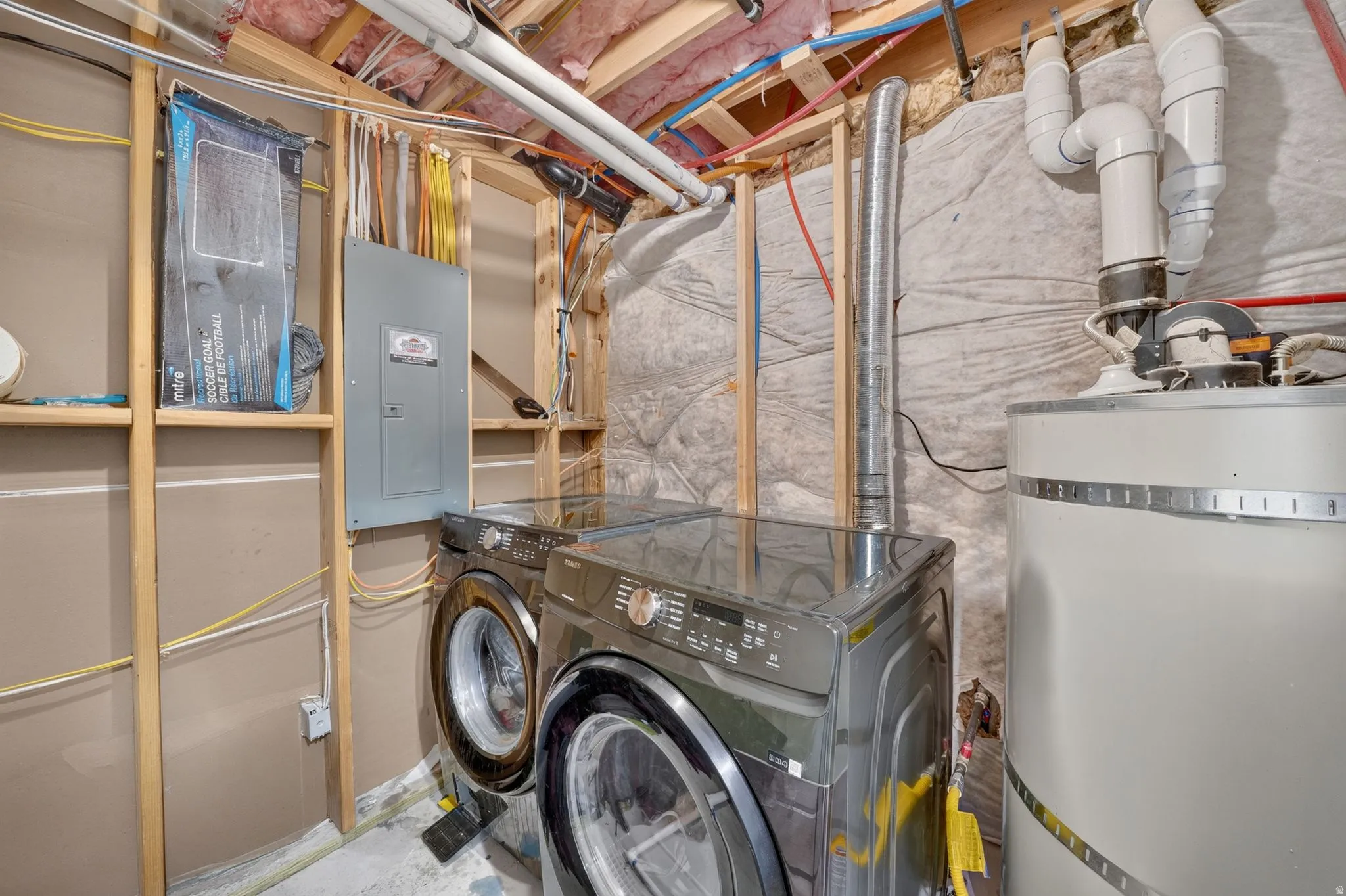 Laundry area featuring a front-loading washer and dryer, electrical panel, and water heater