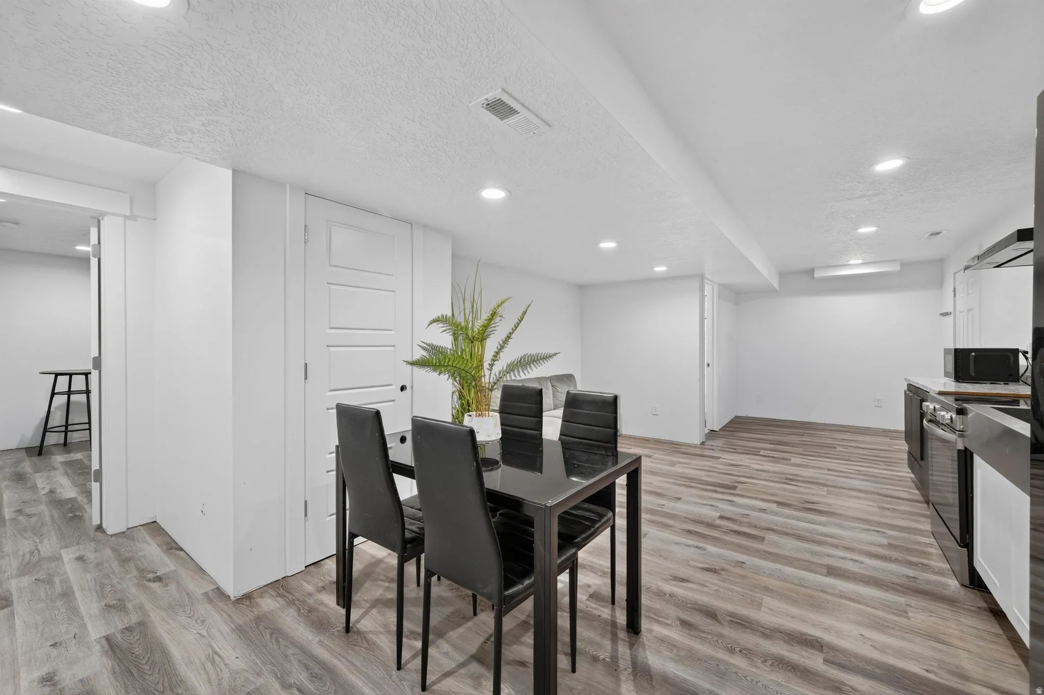 Recessed lighting illuminates the space, featuring wood-finish flooring and white paneled doors