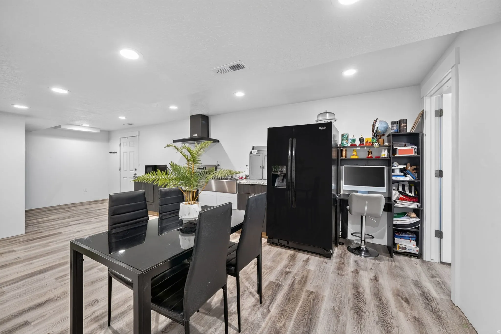 Recessed lighting, wood-finish flooring, and a stainless steel sink with a black range hood