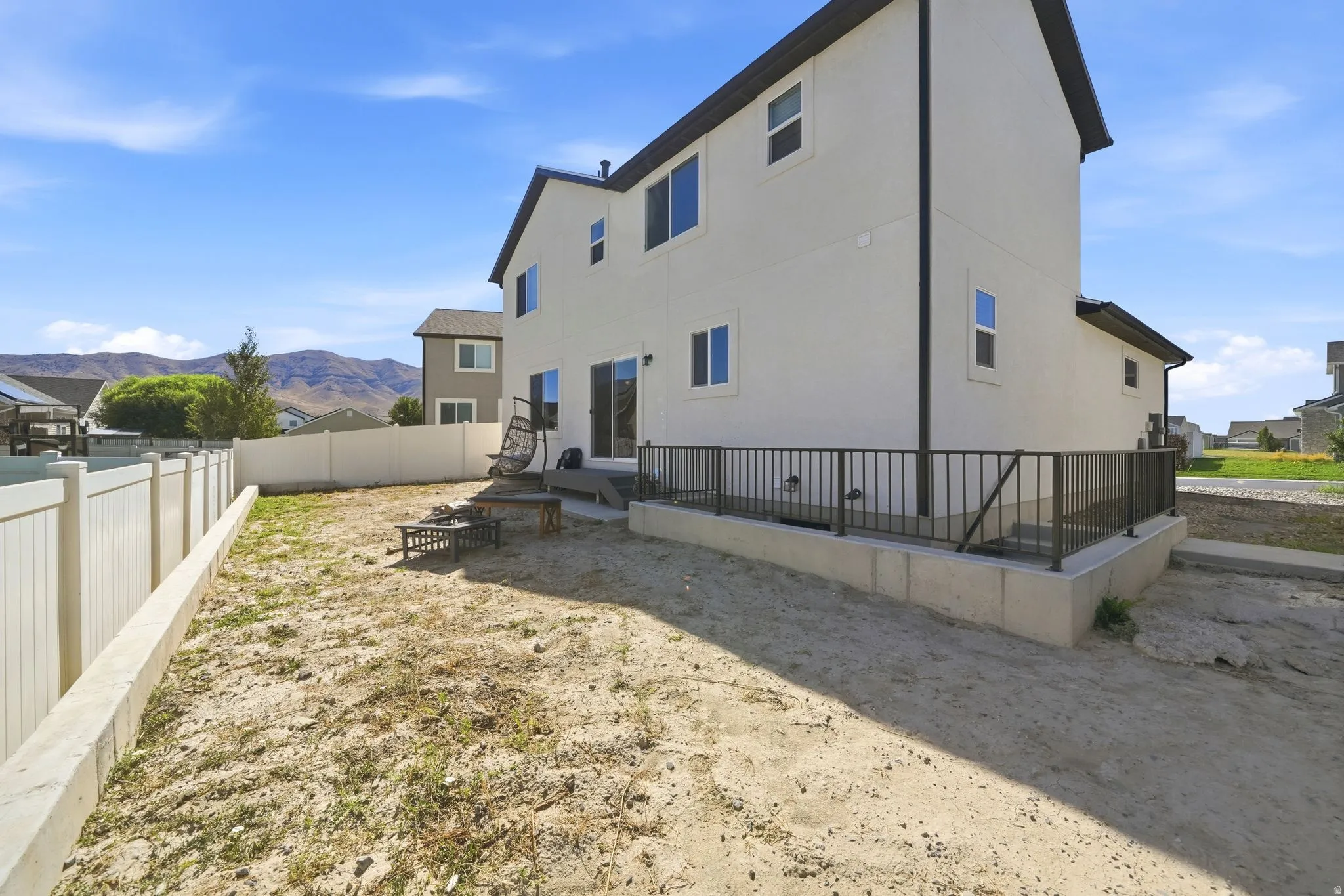 White vinyl privacy fence enclosing a spacious yard with an elevated concrete patio and black metal railing