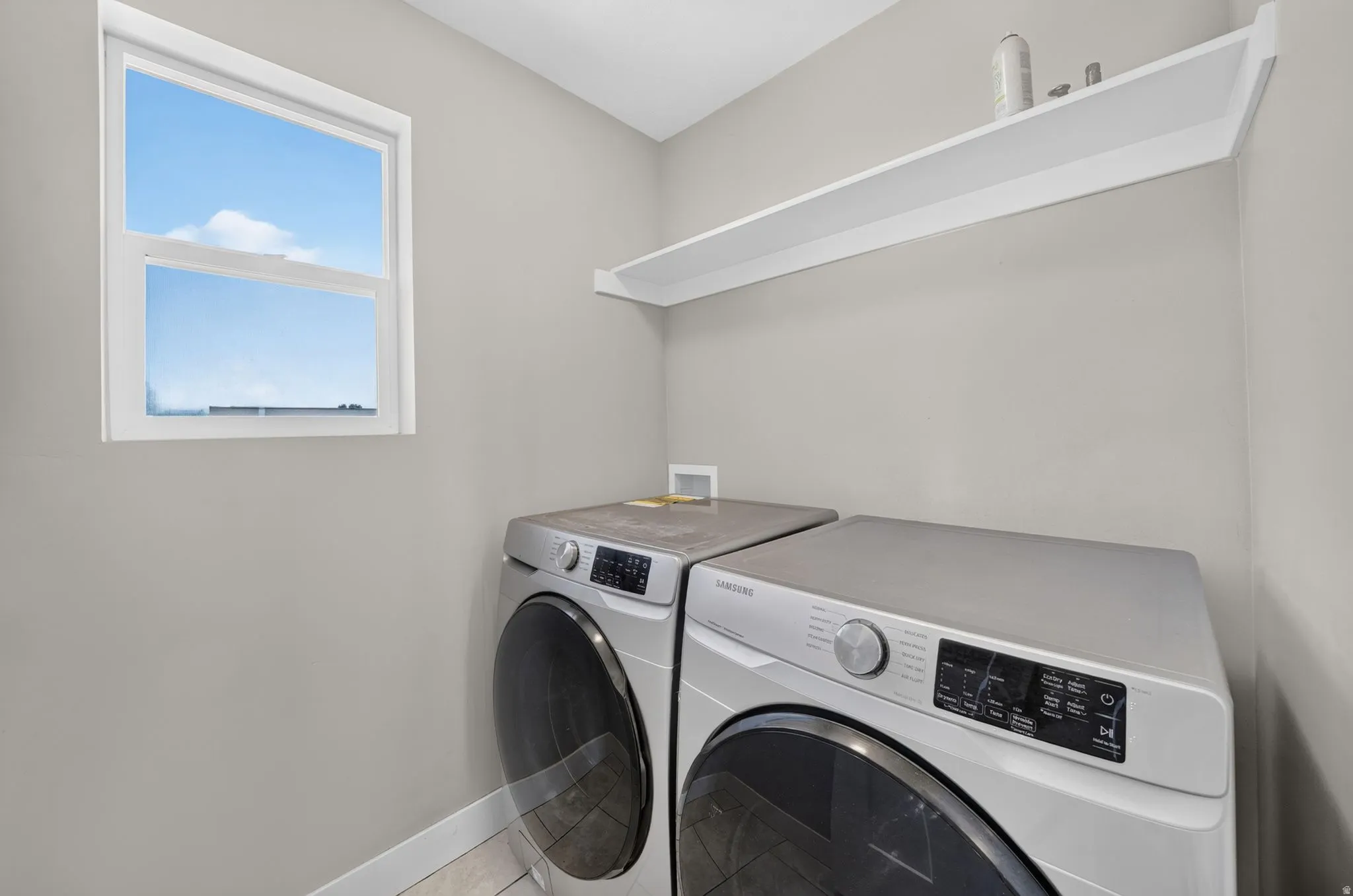 White trim window, light gray wall finish, built-in white shelving, and tile flooring
