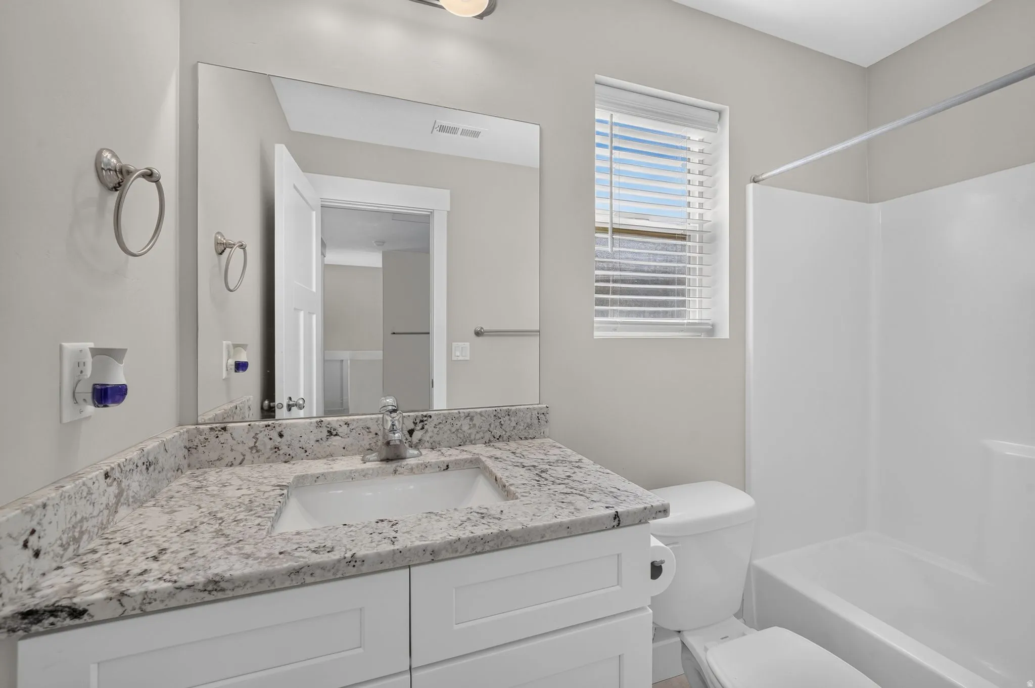 White vanity with a light-toned countertop, integrated sink, and chrome faucet