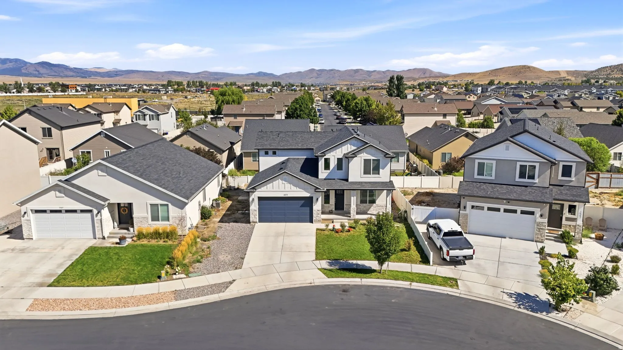Contemporary residential architecture featuring a light gray exterior, two-car garage, and a paved driveway