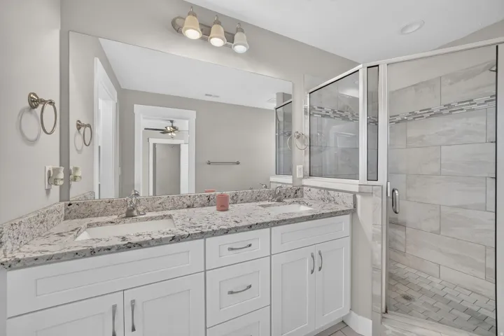 Dual vanity with stone-finish countertop, white cabinetry, and undermount sinks