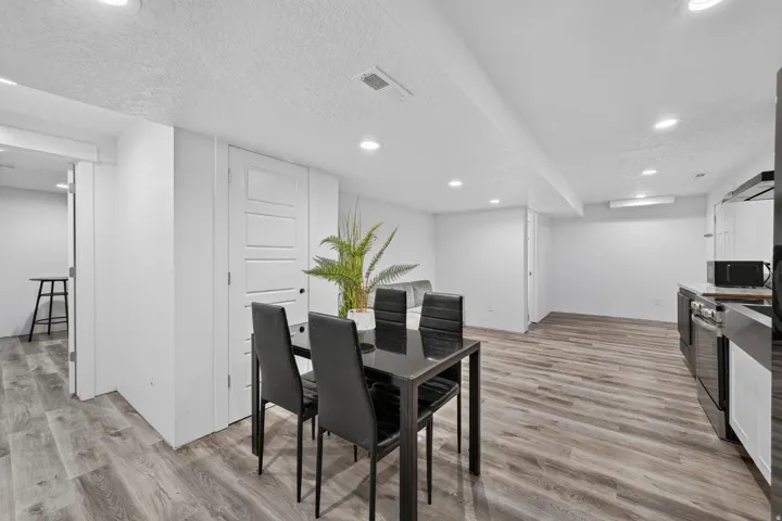 Recessed lighting illuminates the space, featuring wood-finish flooring and white paneled doors