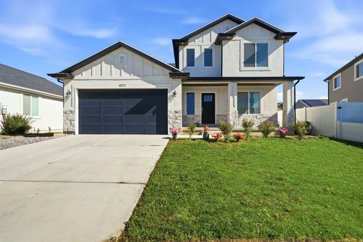 Two-story residence featuring a two-car garage, stone and stucco exterior, and a covered front porch