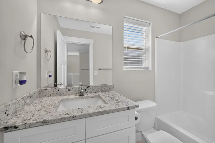 White vanity with a light-toned countertop, integrated sink, and chrome faucet