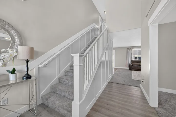 Staircase featuring wainscoting and carpeted treads