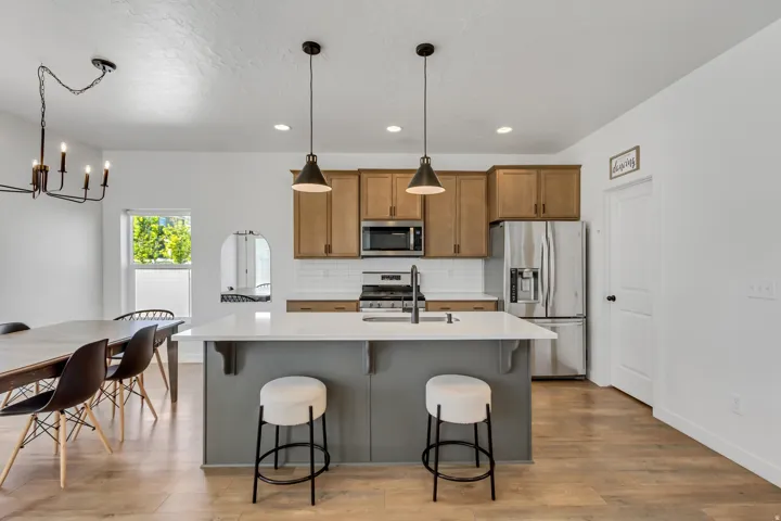 Modern kitchen featuring stainless steel appliances, wood-finish cabinetry, and a gray island with waterfall countertop seating for two