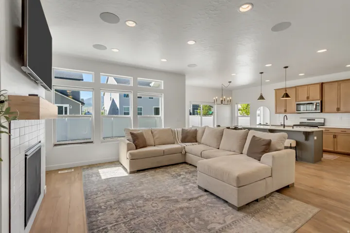 Open-concept living space featuring a fireplace with white subway tile surround, recessed lighting, and large windows