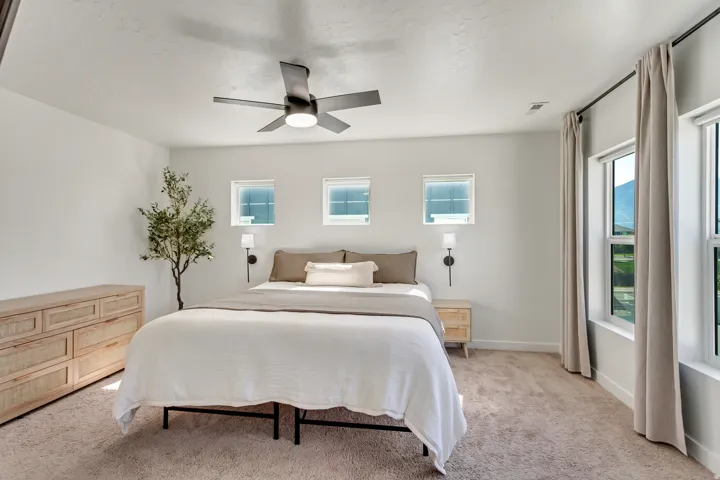 Plush carpeting, four windows, and a ceiling fan with integrated lighting