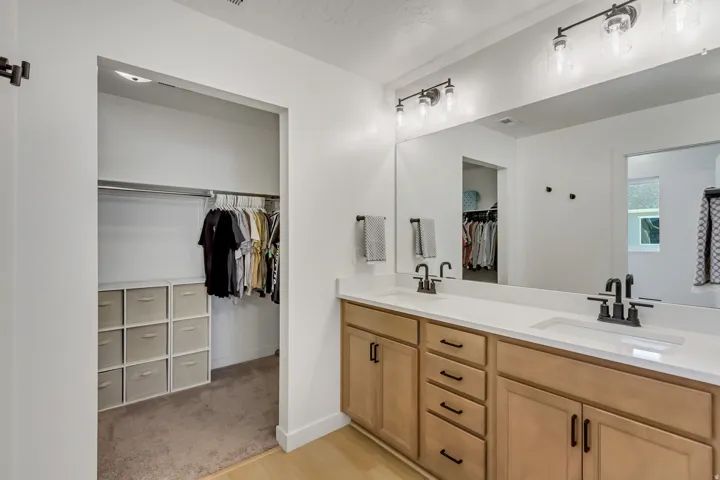 Double vanity with light wood-finish cabinetry, white countertops, and matte black fixtures