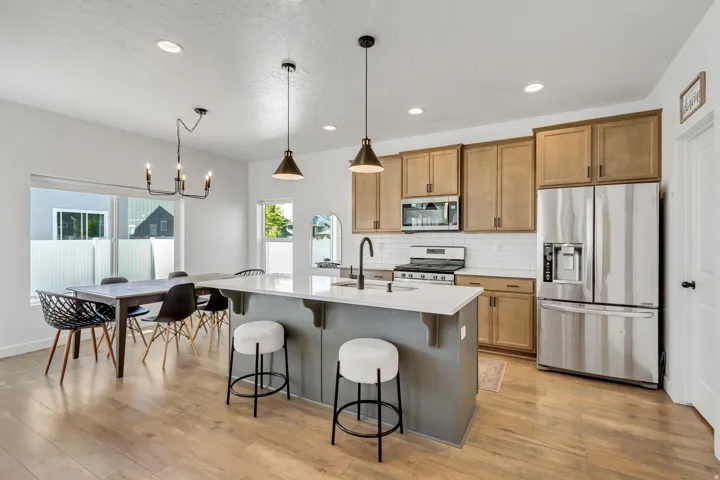 Kitchen featuring stainless steel appliances, wood-finish cabinetry, a white subway tile backsplash, and an island with a white countertop