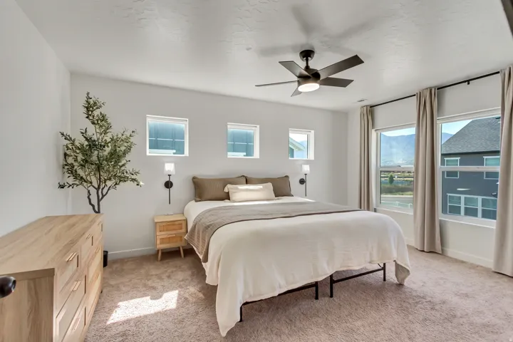 Recessed lighting, ceiling fan with light, large windows with neutral drapes, and wall-mounted sconces